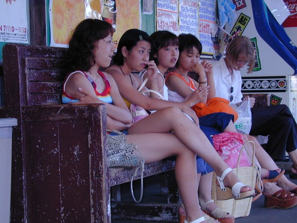 Young ladies sit on a bench and wait for a train